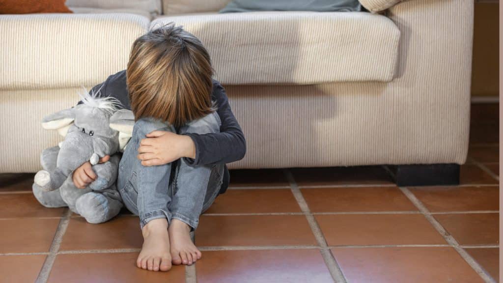 enfant recroquevillé assis par terre